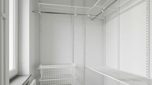 Vit klädkammare med öppna hyllor, trådkorgar och en stång för upphängning. Naturligt ljus från ett fönster till vänster