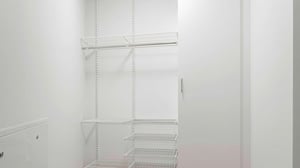 Inflyttningsklart rum med vita väggar och hyllsystem av metall