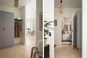 Hall med ljusa trägolv, gråa garderober och väggar i neutral färg. I bakgrunden syns ett vardagsrum och ett badrum med klinkergolv och vitkaklade väggar