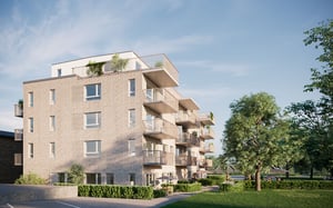 Modern flerfamiljshus med balkonger, omgiven av grönska och parkmiljö under en klar blå himmel