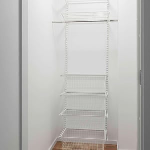 Vit garderobsförvaring med flera trådkorgar och hyllor i metall, monterade i ett litet utrymme med vita väggar