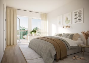 Ljust och luftigt sovrum med en stor säng, beige och gråa sängkläder, gardiner i ljusa toner, en balkong med utsikt och inredning med växter och konstverk på väggen