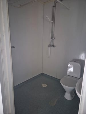 Ett litet, enkelt badrum med duschmunstycke, toalett och handfat