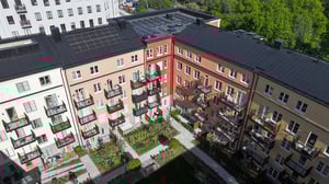 Flerfamiljshus med färgglada fasader, balkonger och en grön innergård med trädgårdsytor