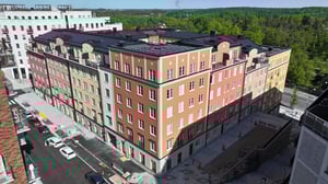 Flerbostadshus med färgglada fasader i en nybyggd stadsdel, omgiven av grönska och moderna byggnader