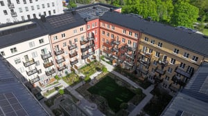 Flerbostadshus med färgglada fasader runt en innergård med gräsmatta, planteringar och gångvägar