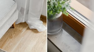 Närbild på ett ljust trägolv bredvid en vit gardin och en marmorfönsterbräda med en grön växt i en kruka