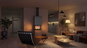 Modernt vardagsrum med mjuk belysning, öppen spis, soffgrupp och stilrena möbler. Växter och dekorativa detaljer framhäver det eleganta och avslappnade intrycket