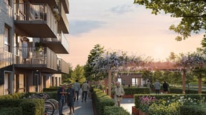 Bostadsområde med lägenhetsbyggnader, balkonger, cykelställ och grönskande trädgårdar vid solnedgång. Människor promenerar och vistas i området