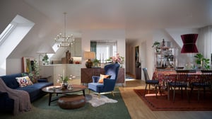 Vardagsrum och matsal i öppen planlösning med modern inredning, inkluderande en blå fåtölj, soffbord, matbord med stolar och dekorativa lampor