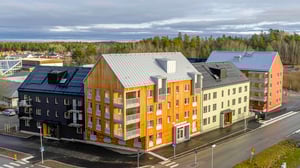 Nybyggd flerfamiljsfastighet med modern design, inkluderande fasader i trä, puts och metall, belägen vid en korsning i ett bostadsområde