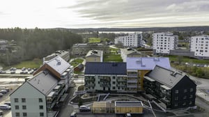 Flerbostadshus i ett bostadsområde med grönområden och parkeringsplatser i bakgrunden