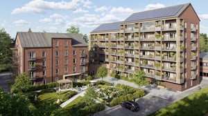 Flerfamiljshus i tegel med solpaneler på taket, omgivna av en grönskande trädgård med gångvägar och sittplatser under en blå himmel