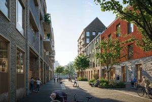 Modern bostadskvarter med flerfamiljshus, träd längs gatan, människor som promenerar och cyklar, samt en öppen trottoar med sittplatser