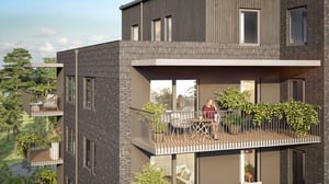 En modern lägenhetsbyggnad med träfasad och flera balkonger, omgivna av grönska. En person sitter på en möblerad balkong