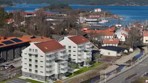 Översiktsbild över samhället med byggnader i ljus fasad i förgrunden, i bakgrunden ligger havet