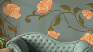 Grön soffa med knappstoppning framför en vägg med en dekorativ blommönstrad tapet i orange och gröna toner