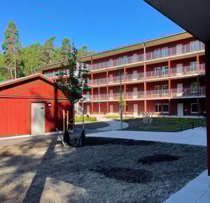 Rött flerbostadshus med balkonger och innergård