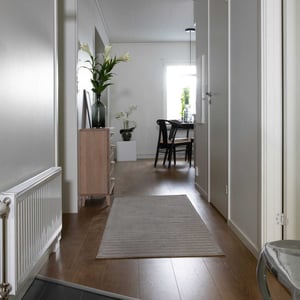 Hall och matsal i ljusa färger, trägolv och enkel inredning