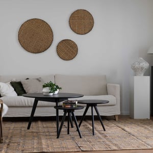 Inflyttningsklar lägenhet med ljus soffa, svarta sidobord och väggdekorationer i ett stilrent vardagsrum