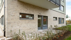 Fasad av modern bostadsbyggnad med tegel och uteplats