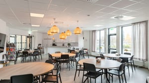 Tomt rum med gemensam matsal, bord och stolar samt köksdel