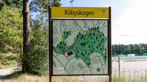 Skylt med områdeskarta över Råbyskogen i grönskande utomhusmiljö