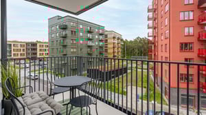 Utsikt från balkong mot flerbostadshus i olika färger och innergård