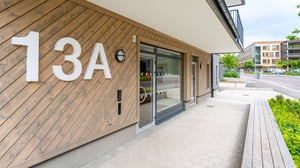 Entré till flerbostadshus med träfasad och husnummer 13A