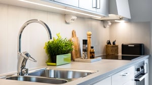 Köksbänk med diskho, kromad blandare, spishäll och köksredskap