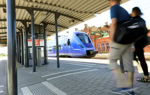 Två personer går på en tågperrong vid ett blått tåg