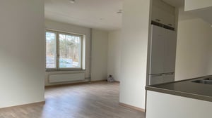 Inflyttningsklar lägenhet med ljus öppen planlösning, stort fönster och köksdel