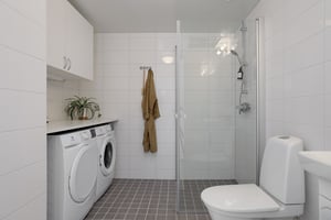 Modernt badrum med duschhörna, tvättmaskin och torktumlare