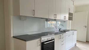 Tomt kök med vita skåp, mörk bänkskiva och spis i inflyttningsklar lägenhet