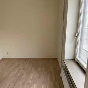 Inflyttningsklar lägenhet med ljusa väggar, trägolv och stort fönster