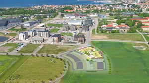 Flygvy över ett bostadsområde med nybyggda flerbostadshus, vägar och gröna fält. Planillustration för kommande bostadsområde vid Planetgatan