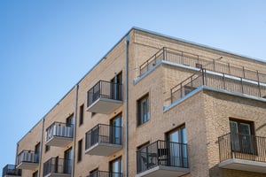 Flerfamiljshus med balkonger i ljus tegel och blå himmel