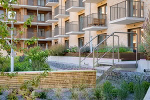 Lägenhetsfasad med balkonger och grönskande innergård