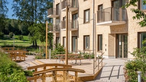 Lägenhetshus med balkonger och uteplats i grönskande bostadsområde