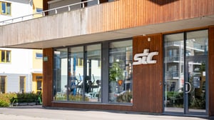 Exteriör av en lokal med stora fönster och träfasad, märkt stc