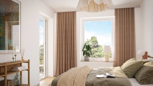 Sovrum med dubbelsäng, stort fönster och beige gardiner