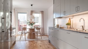 Ljust kök med matplats, grå köksluckor, träbord och stora fönster med utgång till balkong