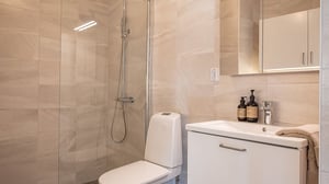 Inflyttningsklart badrum med dusch, toalett och handfat i ljusa beige toner