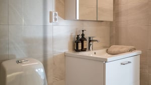 Badrum med handfat, spegelskåp, tvåldispensrar och handduk