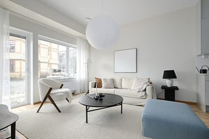 Vardagsrum med soffa, fåtölj, soffbord och stora fönster