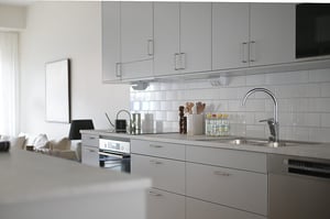 Inflyttningsklart kök med vita skåpsluckor, kaklad vägg och rostfri diskho