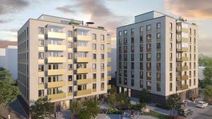 Två moderna bostadshus med balkonger och gröna gårdsytor i kvällsljus