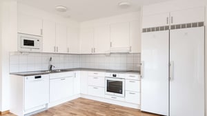 Inflyttningsklar lägenhet med vitt kök, kyl och frys, ugn, diskmaskin och ljus träparkett