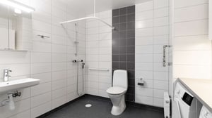 Inflyttningsklart badrum med vita kakelväggar, dusch, toalett och handfat