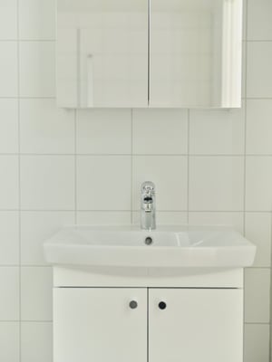 Vitt handfat med spegelskåp i ett kaklat badrum